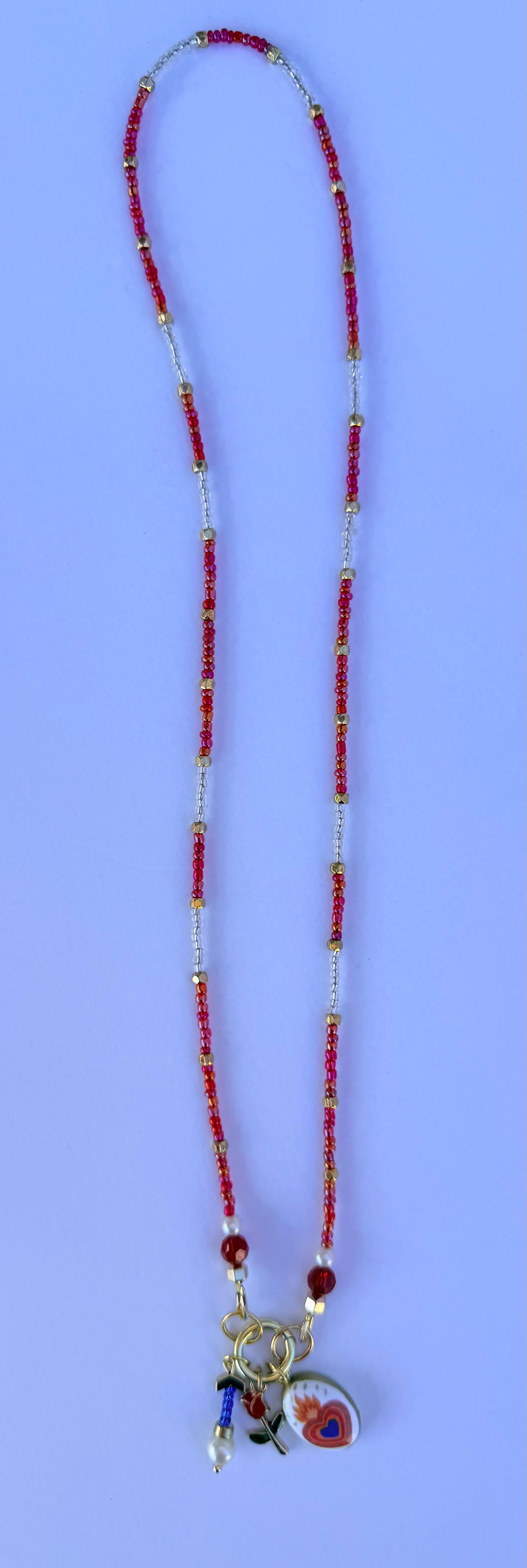 AMOR companion necklace in iridescent glass beads and ivory glass pearls with milagro heart, glass bead charm, and gold rose